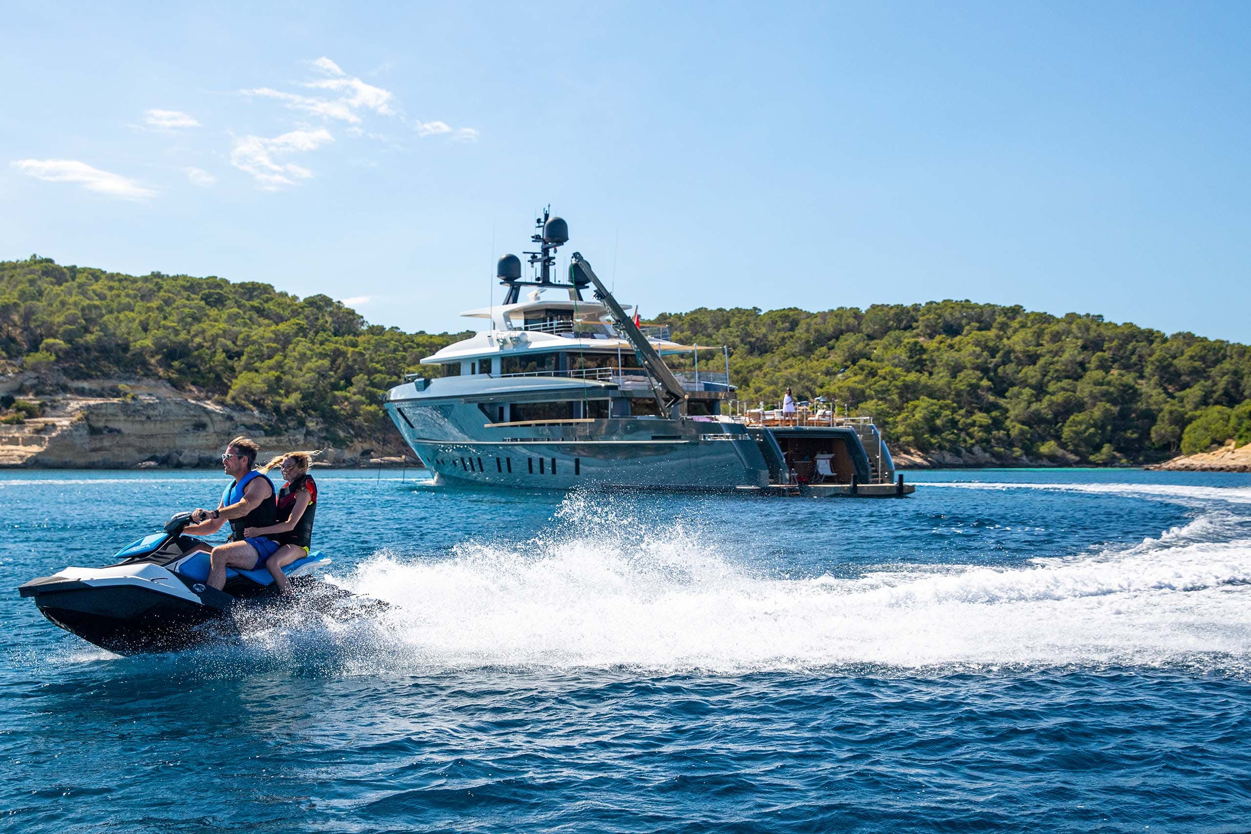 Couple playing on jet ski next to motor yacht MOKA during a summer yacht charter vacation